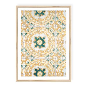 May include: A framed wall art print featuring a repeating pattern of square tiles. The design displays a symmetrical arrangement of yellow scrollwork and dark teal floral motifs on a white background, enclosed in a light-colored wooden frame.
