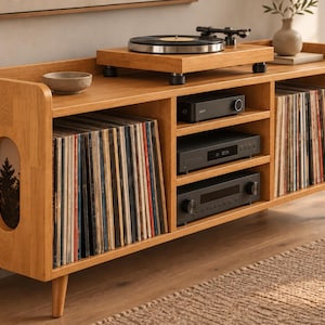 May include: A light brown wooden media console with tapered legs, featuring open shelving filled with vinyl records, a turntable on the top surface, and three stacked black electronic audio components in the center compartment.
