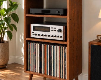 Puede incluir: Un mueble de almacenamiento multimedia alto de madera con cuatro estantes abiertos. El estante superior sostiene un tocadiscos, los estantes intermedios albergan equipos de audio y el estante inferior contiene una colección de discos de vinilo.