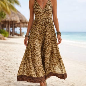 May include: A floor-length sleeveless dress featuring a brown and tan leopard print pattern. The garment has a V-neckline, a fitted bodice, and a flowing skirt that ends with a wide, dark brown horizontal band with a repeating geometric pattern.