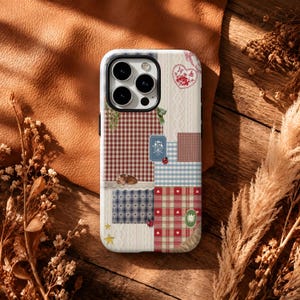 May include: A smartphone case featuring a patchwork design of red, blue, and white gingham, cable knit textures, and small illustrations including a heart, a mouse, stars, and a ladybug. The case has a black camera cutout for three lenses.