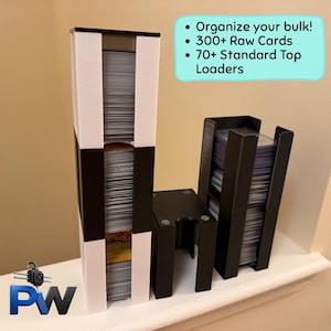 Puede incluir: Una torre de almacenamiento vertical blanca y negra llena de cartas, una unidad de almacenamiento negra vacía más pequeña y una torre vertical negra llena de fundas rígidas. El texto dice: Organize your bulk! 300+ Raw Cards 70+ Standard Top Loaders.