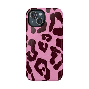Puede incluir: Una funda para smartphone con un patrón de leopardo repetitivo en tonos rosa claro y granate oscuro. La funda presenta un diseño de anillo magnético circular visible en la parte posterior y recortes para las dos lentes de la cámara.