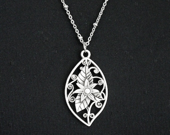 May include: A silver necklace with a delicate pendant featuring a floral design. The pendant is shaped like a leaf with a flower in the center.