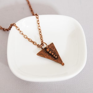 May include: A copper triangle pendant necklace with a hammered finish and a row of small copper beads down the center.