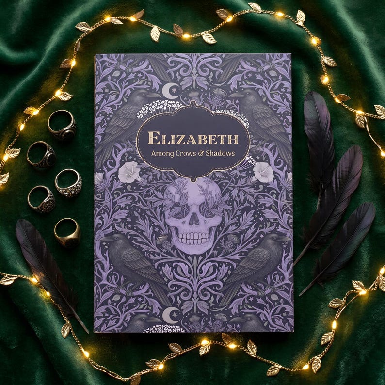 Pu&ograve; includere: Un libro rettangolare intitolato Elizabeth Among Crows & Shadows con una copertina viola raffigurante un teschio, corvi e motivi floreali. Cinque anelli in metallo sono disposti a sinistra e due piume nere a destra del libro.