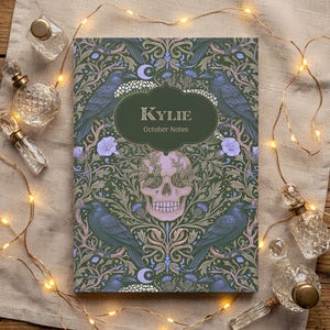 Pu&ograve; includere: Un taccuino rettangolare con copertina verde scuro caratterizzato da un motivo ripetuto di corvi neri, fiori viola chiaro e un teschio rosa pallido centrale. Un'etichetta ovale verde scuro al centro riporta il testo Kylie October Notes.