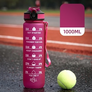 May include: A magenta 1000ml water bottle with a black lid and a pink carrying strap. The bottle features white time markers from 8AM to 7PM with motivational text and water drop icons. A yellow tennis ball is positioned next to the bottle.