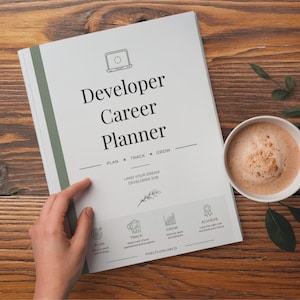 May include: A white Developer Career Planner book with a green spine, featuring a laptop icon, the text "Developer Career Planner", "PLAN • TRACK • GROW", "LAND YOUR DREAM DEVELOPER JOB", and four bottom icons labeled "PLAN", "TRACK", "GROW", and "ACHIEVE".