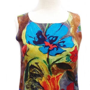 May include: A sleeveless dress with a colorful floral print. The print features large blue, red, yellow, and green flowers on a brown background.