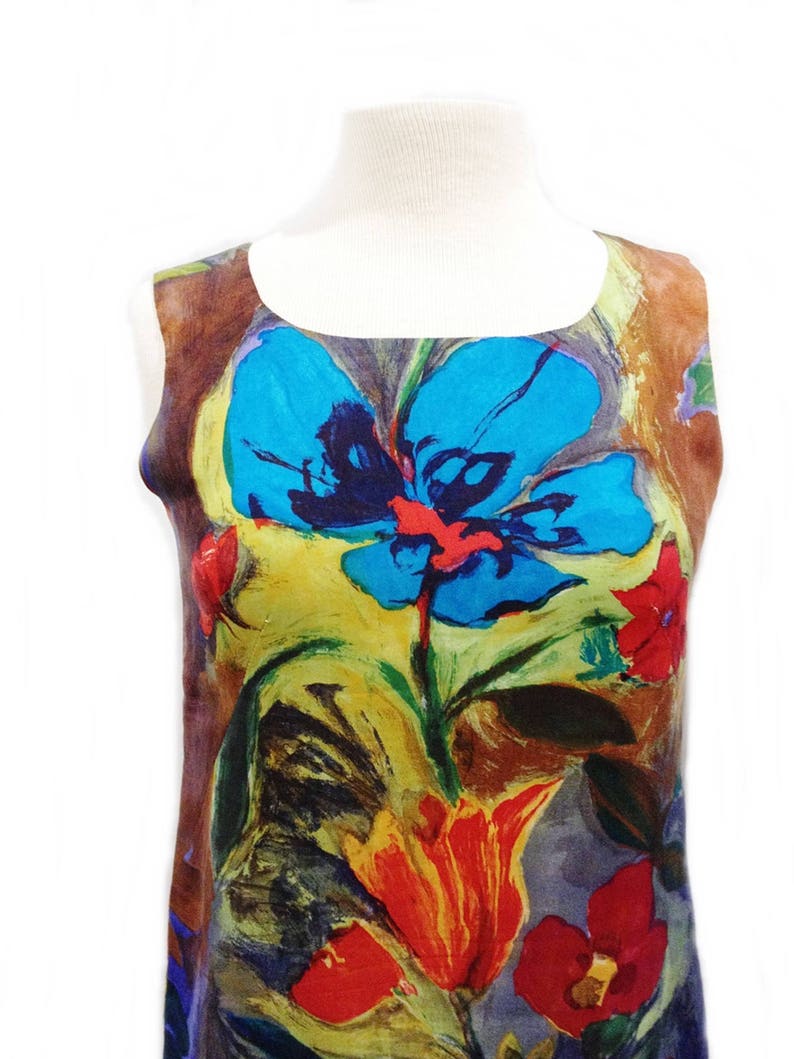 May include: A sleeveless dress with a colorful floral print. The print features large blue, red, yellow, and green flowers on a brown background.