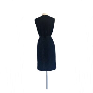 May include: A sleeveless black dress with a textured fabric. The dress has a fitted bodice and a slightly flared skirt.