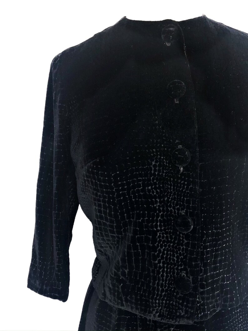 May include: A black velvet dress with a textured pattern and button closures.