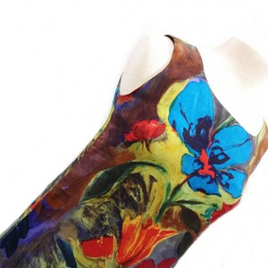 May include: A sleeveless dress with a colorful floral print featuring blue, red, yellow, and green hues. The dress has a brown background and a loose, flowing silhouette.