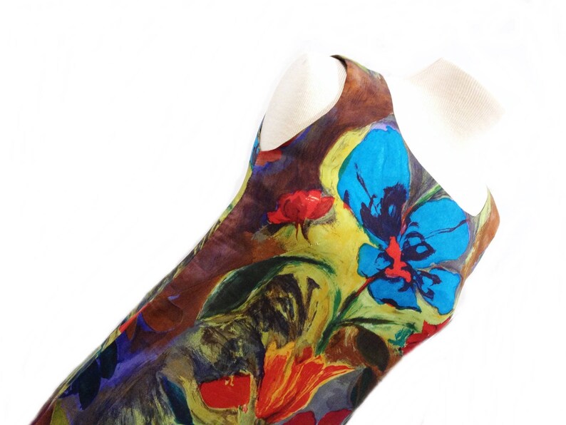 May include: A sleeveless dress with a colorful floral print featuring blue, red, yellow, and green hues. The dress has a brown background and a loose, flowing silhouette.