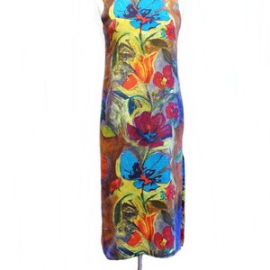 May include: A sleeveless maxi dress with a colorful floral print. The dress features a variety of flowers in shades of red, orange, yellow, blue, and purple. The background of the dress is a brown color.