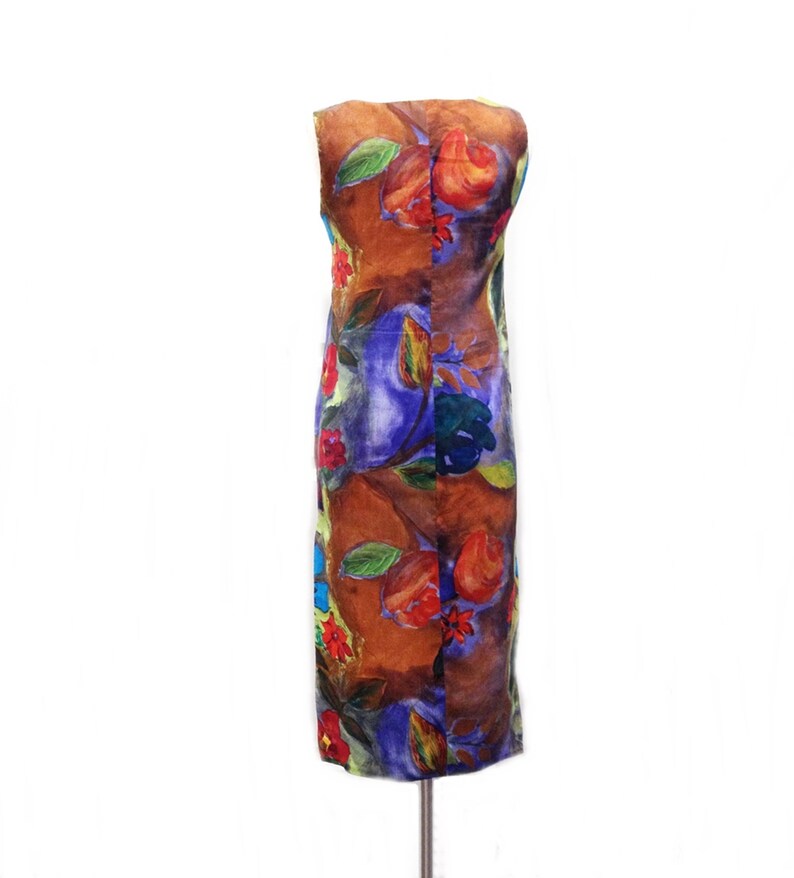 May include: A sleeveless dress with a brown, blue, green, red, and yellow floral print. The dress is on a white background.