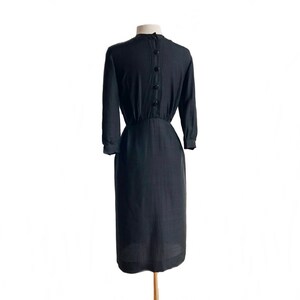 May include: A black knee-length dress with a button-up back and a fitted waist.