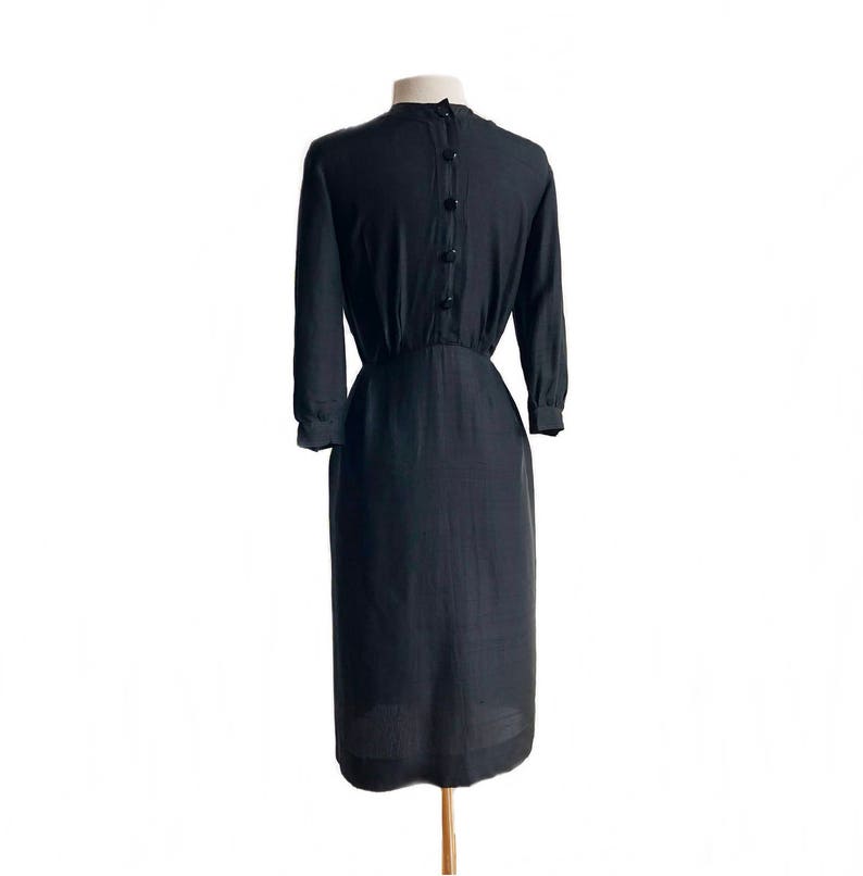 May include: A black knee-length dress with a button-up back and a fitted waist.