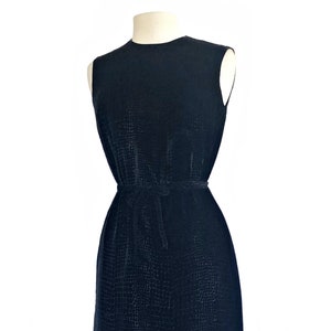 May include: A sleeveless black dress with a textured pattern and a matching fabric belt.