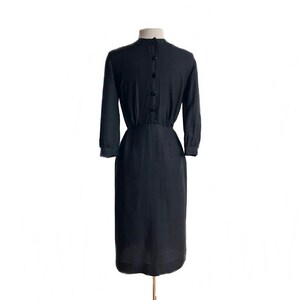 May include: A black, knee-length dress with a button-up back and a fitted waist.