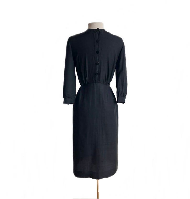 May include: A black, knee-length dress with a button-up back and a fitted waist.