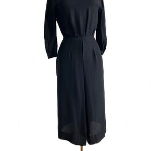 May include: A black, long-sleeved, knee-length dress with a fitted bodice and a slightly flared skirt.