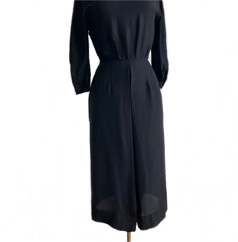 May include: A black, long-sleeved, knee-length dress with a fitted bodice and a slightly flared skirt.