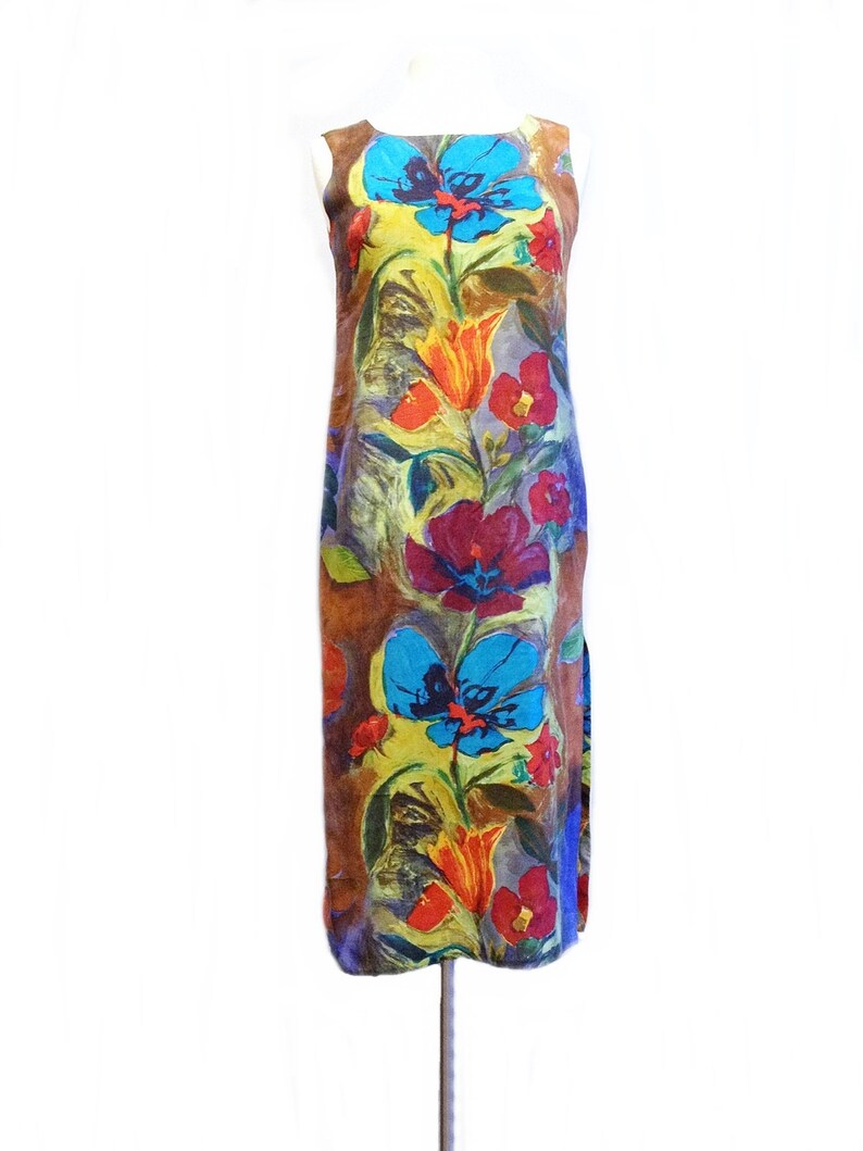 May include: A sleeveless maxi dress with a colorful floral print. The dress features a variety of flowers in shades of red, orange, yellow, blue, and purple. The background of the dress is a brown color.