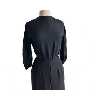 May include: A black, long-sleeved dress with a high neckline and a fitted bodice. The dress has a gathered skirt and a slightly flared silhouette.
