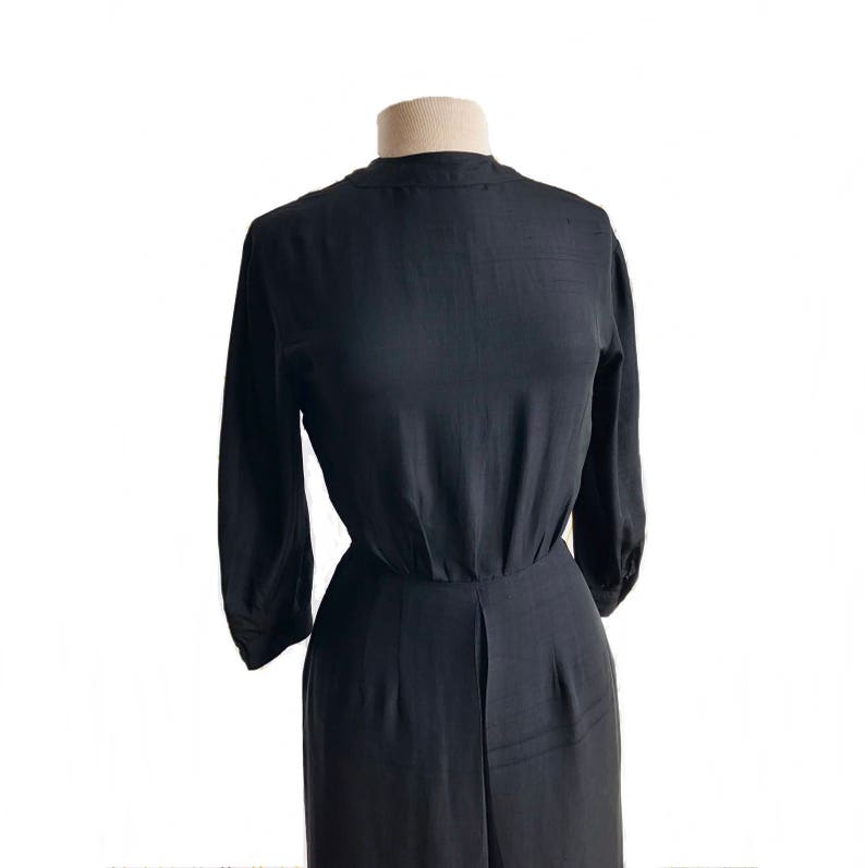 May include: A black, long-sleeved dress with a high neckline and a fitted bodice. The dress has a gathered skirt and a slightly flared silhouette.