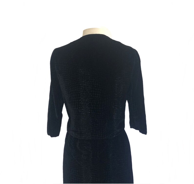 May include: A black velvet dress with a textured pattern. The dress has a round neckline and three-quarter sleeves.