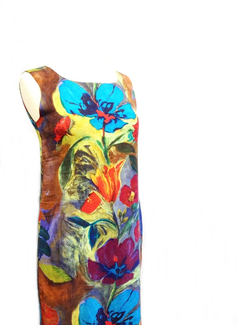 May include: A sleeveless dress with a colorful floral print. The dress features a variety of flowers in shades of blue, red, yellow, and purple. The background of the dress is a brown color.