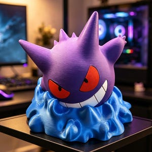 May include: A purple Gengar figure with spiky ears and a wide grin, featuring red eyes and a white mouth. The character is emerging from a textured, wavy blue base that mimics a liquid or cloud-like effect, creating a distinct three-dimensional appearance.