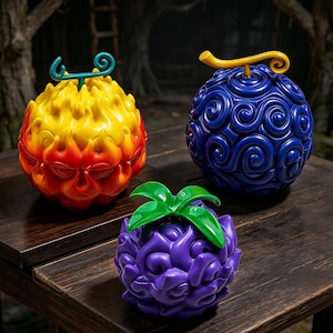 May include: Three spherical decorative objects inspired by fantasy fruit. One is yellow and red with flame-like textures, one is dark blue with swirling patterns and a yellow stem, and one is purple with green leaves and a textured surface.