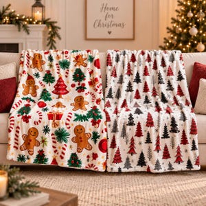 May include: A white throw blanket featuring a repeating pattern of gingerbread people, Christmas trees, candy canes, and wrapped gifts, alongside a second white throw blanket with a repeating pattern of red, black, and grey Christmas trees.