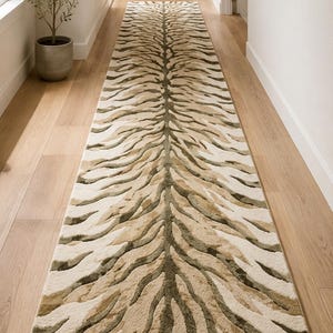 May include: A long, rectangular runner rug featuring a symmetrical, organic pattern of wavy, textured stripes in shades of cream, beige, and olive green. The design radiates from a central spine, creating a fluid, nature-inspired visual effect.