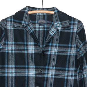 May include: A blue and gray plaid flannel shirt with a button-up front and a collared neckline. The shirt has the Pendleton brand label on the front.