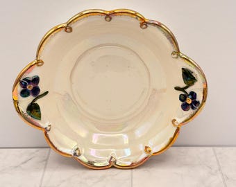Stara misa z połyskliwego materiału w kwiaty, opalizująca ceramiczna miska, fioletowe kwiaty, złote wykończenie