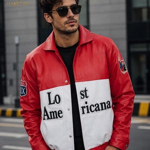 May include: A red and white leather jacket featuring a black collar, silver snap buttons, and black lettering that reads Lost Americana across the front. The sleeves display circular patches with graphic designs, and the jacket is worn over a black shirt.