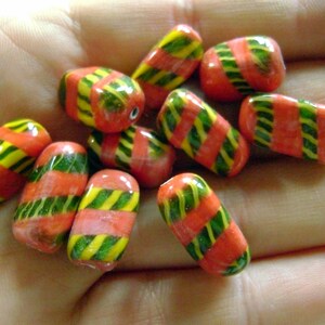 May include: A collection of red and green striped glass beads. The beads are all rectangular in shape and have a glossy finish.