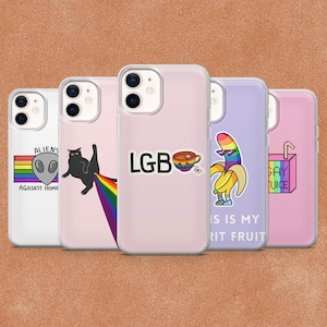 Puede incluir: Cinco fundas transparentes para smartphone con varios diseños: un alienígena con una bandera arcoíris y el texto ALIENS AGAINST HOMOPHOBIA, un gato negro con una estela arcoíris, el texto LGB con una taza arcoíris, un plátano arcoíris y un zumo.
