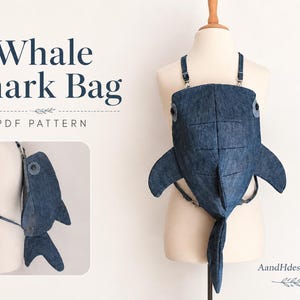 May include: A dark blue denim whale shark bag with side fins, a dorsal fin, and a tail. The bag features button eyes and adjustable straps. Text on the image reads Whale Shark Bag PDF Pattern and AandHdesignstore. The bag is shown from front and side.