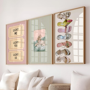 May include: A set of three framed wall art prints. The left print features three pink tickets with the text LUCKY ME, LUCKY YOU, and LUCKY US. The center print shows a leopard on a striped background. The right print displays six high-heeled shoes.