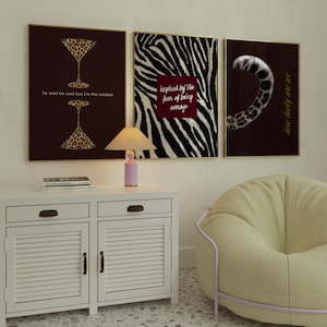 May include: Three framed wall art prints featuring animal print motifs. The left print shows two leopard-print martini glasses with the text he said be cool but I'm the coolest. The centre print has a zebra pattern and a red box with the text inspired by the fear of being average. The right print displays a leopard tail and the text how lucky are we.