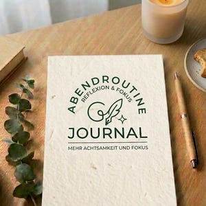 Könnte beinhalten: Ein rechteckiges Journal mit einem strukturierten, cremeweißen Einband und dunkelgrünem Text, der ABENDROUTINE REFLEXION & FOKUS JOURNAL MEHR ACHTSAMKEIT UND FOKUS lautet, ergänzt durch ein stilisiertes Federkiel-Symbol und einen kleinen vierzackigen Stern.