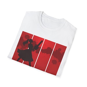 May include: A white t-shirt featuring a graphic print of a black silhouette of a person with a ponytail wearing a dress and holding a chainsaw. The design is set against a red background with vertical white stripes and dark red paint splatters.