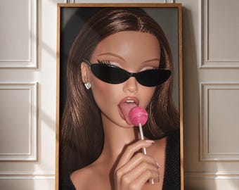 May include: A framed wall art print featuring a doll with long brown hair, wearing black oval sunglasses and a small silver earring. The doll has a pink lollipop in its mouth, with its tongue visible, and is holding the lollipop stick.