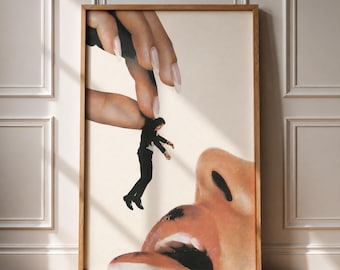 May include: A surreal art print in a wooden frame featuring a giant hand with long manicured nails holding a tiny person in a black suit above a large, open mouth. The composition uses a cream-colored background and realistic skin tones.