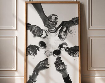 May include: A black and white framed wall art print depicting multiple hands holding clear glass wine glasses in a circular arrangement, with the glasses meeting in the center. The hands are adorned with various metal wristwatches and bracelets.